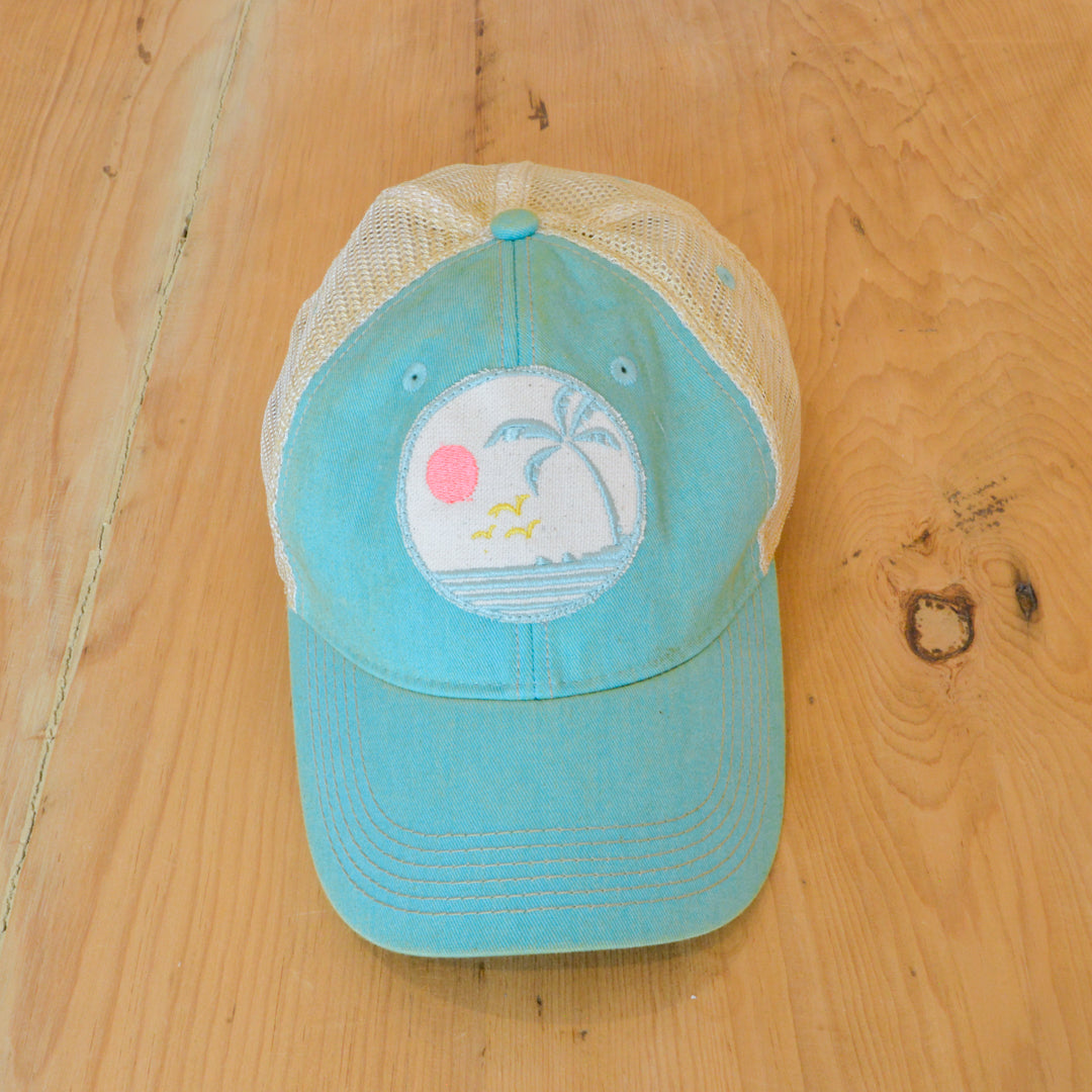 The Goat Stock Sunrise distressed baseball hat featuring an embroidered patch on a light blue trucker style hat at Inner Beach Co, Toronto, Ontario, Canada