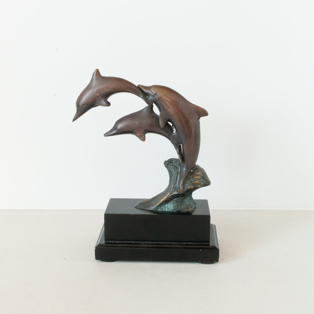 Vintage bronze figurine depicting a trio of dolphins jumping, mounted on a wood pedestal base at Inner Beach Co, Toronto, Canada