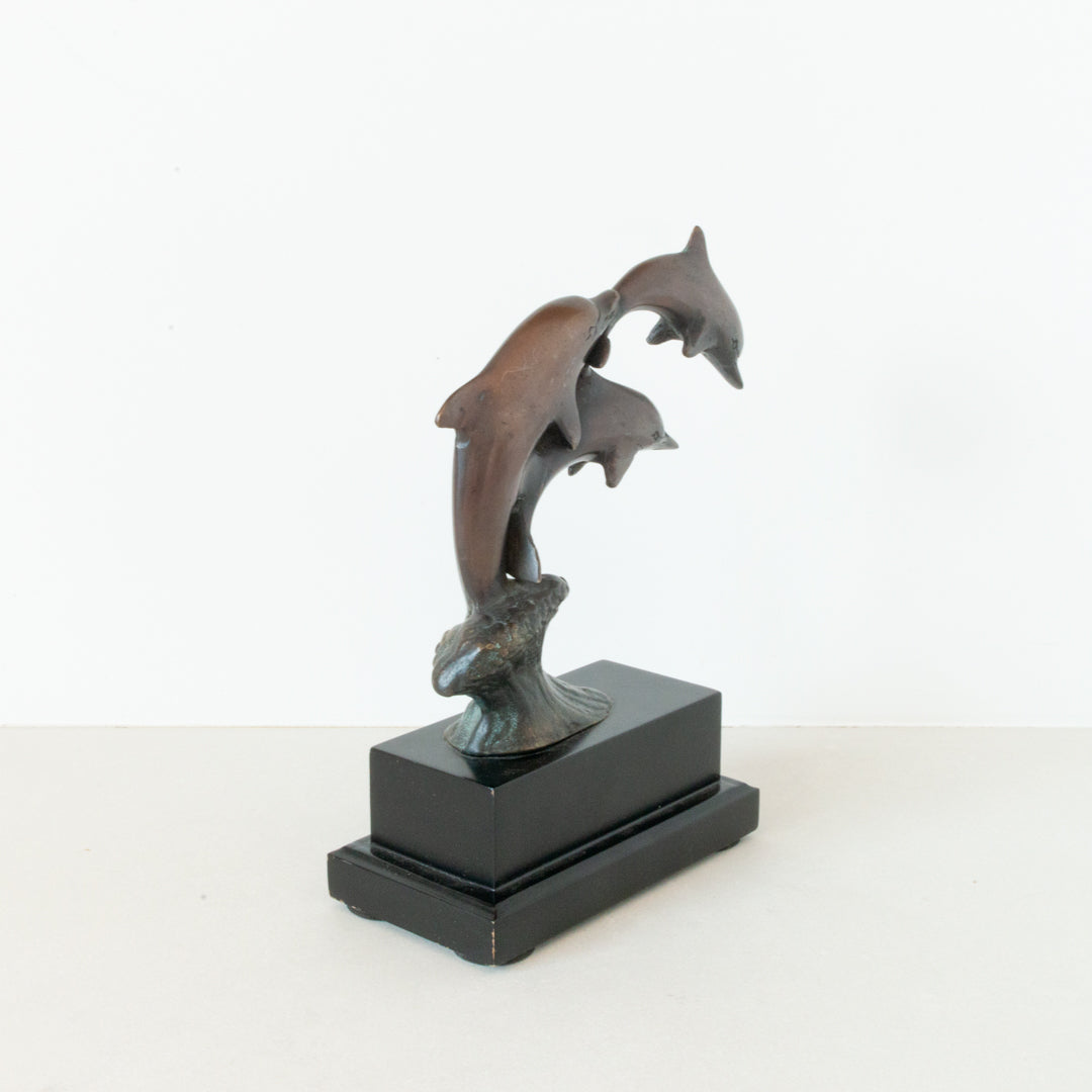 Vintage bronze figurine depicting a trio of dolphins jumping, mounted on a wood pedestal base at Inner Beach Co, Toronto, Canada